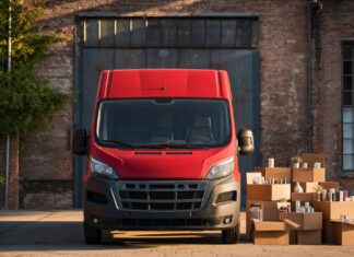 Roter Kurier-Van vor Paketboxen in einem Industriehof, warmes Tageslicht