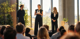 Gründerteam präsentiert ein Produkt auf einer Bühne vor Publikum im warmen Tageslicht