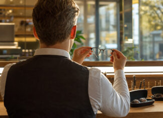 Optiker hält eine Brille in einer modernen Werkstatt bei natürlichem Licht