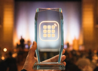 Hand hält gläsernen Pokal mit App-Symbol bei einer Preisverleihung