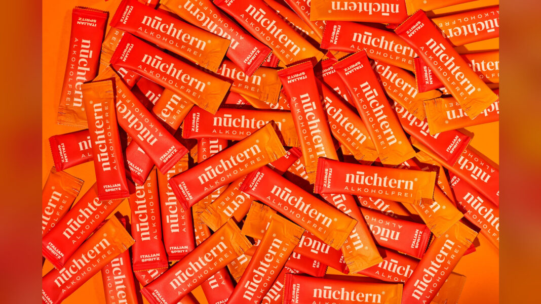 nüchtern bei der Höhle der Löwen: Italian Spritz aus dem Beutel Viele Portionsbeutel des alkoholfreien Italian Spritz von nuechtern liegen dicht an dicht auf orangem Grund