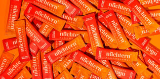 Viele Portionsbeutel des alkoholfreien Italian Spritz von nuechtern liegen dicht an dicht auf orangem Grund