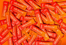 Viele Portionsbeutel des alkoholfreien Italian Spritz von nuechtern liegen dicht an dicht auf orangem Grund