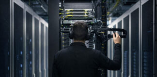 Serverrack im Rechenzentrum, davor ein Techniker von hinten bei der Wartung