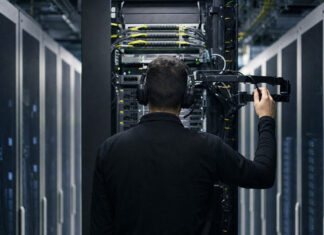 Serverrack im Rechenzentrum, davor ein Techniker von hinten bei der Wartung
