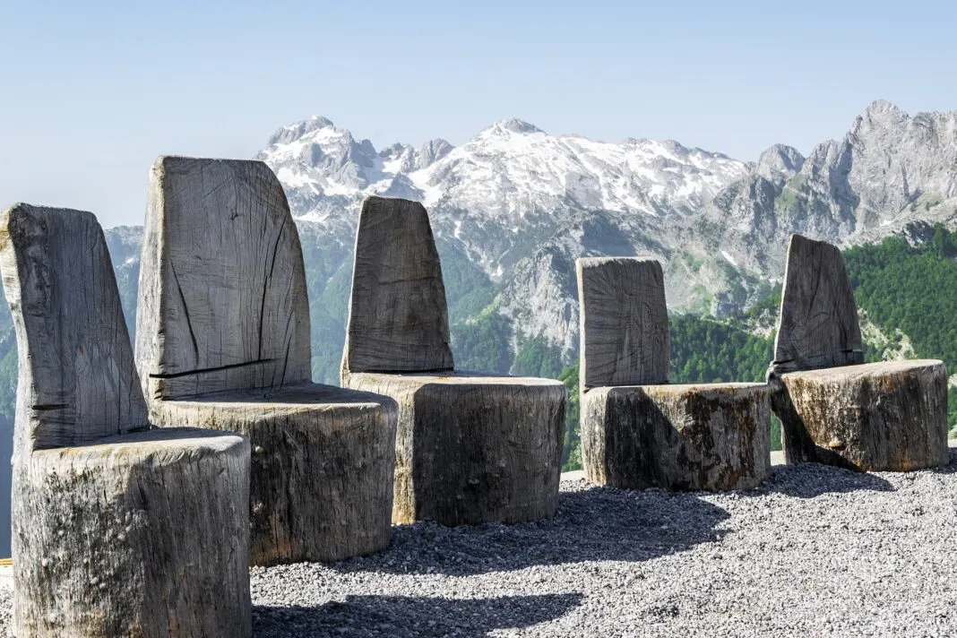 Holzstühle an einem Aussichtspunkt vor den schneebedeckten Gipfeln der Albanischen Alpen