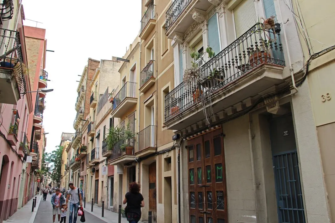 Schmale Wohnstraße in Gracia mit Balkonen, Pflanzen und Hausnummern an den Fassaden
