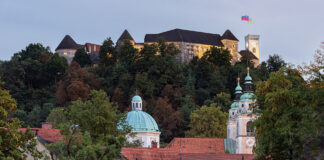Burg von Ljubljana über bewaldetem Hang, darunter die Kuppel und die Türme der Altstadt