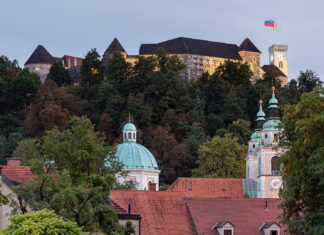 Burg von Ljubljana über bewaldetem Hang, darunter die Kuppel und die Türme der Altstadt