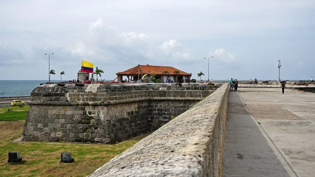 Stadtmauer von Cartagena mit kolumbianischer Flagge, Kanonen und dem Meer dahinter