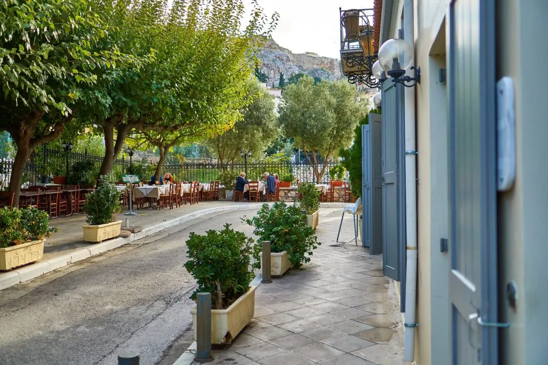 Ruhige Gasse im Athener Viertel Plaka mit Tavernentischen und dem Felsen der Akropolis