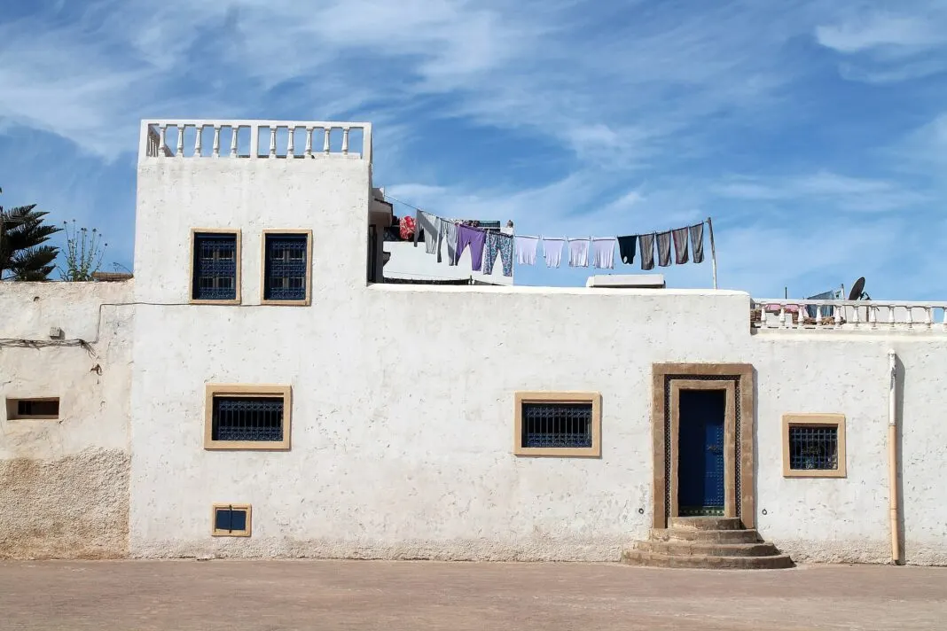 Weiss getünchtes Wohnhaus mit blauen Fenstergittern und Waescheleine in der Medina von Rabat