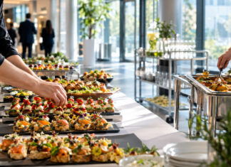 CATERWINGS – Catering mit Raketenantrieb Catering-Platten werden im hellen Foyer eines Unternehmens auf einem Buffet angerichtet.