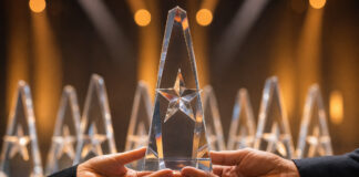 Hände halten eine gläserne Trophäe auf einer Preisverleihungsbühne