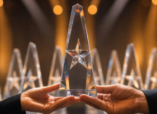 Hände halten eine gläserne Trophäe auf einer Preisverleihungsbühne