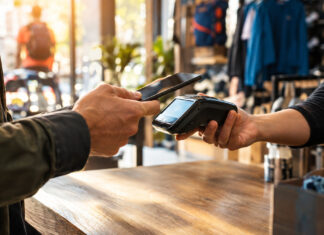 Kunde bezahlt im Sportgeschäft kontaktlos mit Smartphone am Kartenterminal.