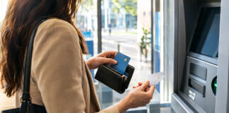 Selbständige trennt Karten am Bankautomaten in einer hellen Filiale