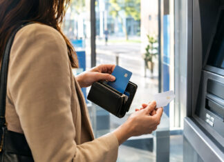 N26 Business – ein Konto speziell für Selbständige Selbständige trennt Karten am Bankautomaten in einer hellen Filiale