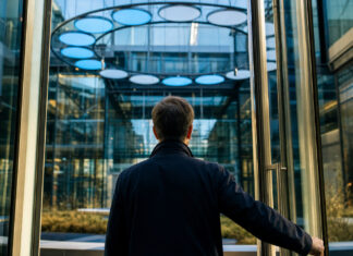 Digital Hub Initiative: das dynamische Dutzend Gläsernes Innovationszentrum mit leuchtenden Modulen und einer Person am Zugangstor