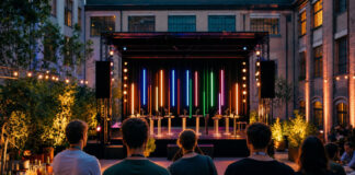 Festivalbühne im Innenhof, davor Besucher von hinten, mit Konferenz-Elementen und Abendlicht