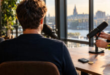 Rückenansicht eines Gründers im Podcast-Interview, Hände am Mikrofon und einer Krypto-Wallet