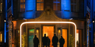 Gruppe vor beleuchteter Berliner Hausfassade bei Nacht mit Eventlichtern