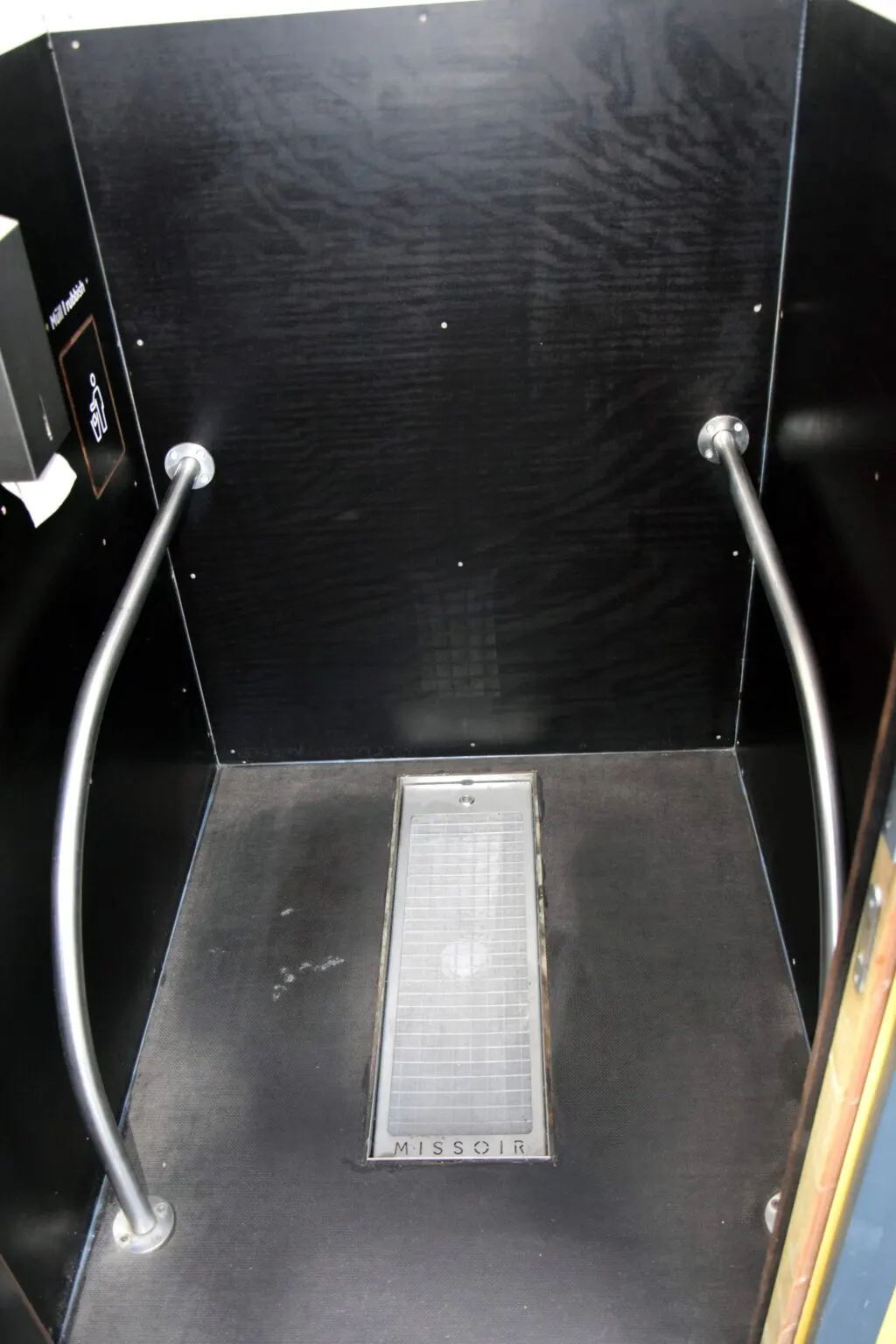 Hockurinal mit Haltegriffen in einer dunkel verkleideten oeffentlichen Toilette in Berlin-Marzahn