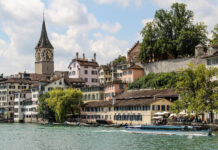 Auswandern nach Zürich: Kosten, Anmeldung und Gründung Altstadthäuser und der Turm von Sankt Peter am Ufer der Limmat in Zürich