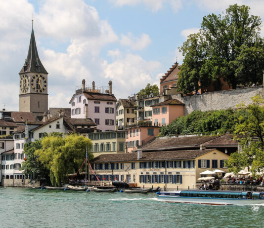 Altstadthäuser und der Turm von Sankt Peter am Ufer der Limmat in Zürich
