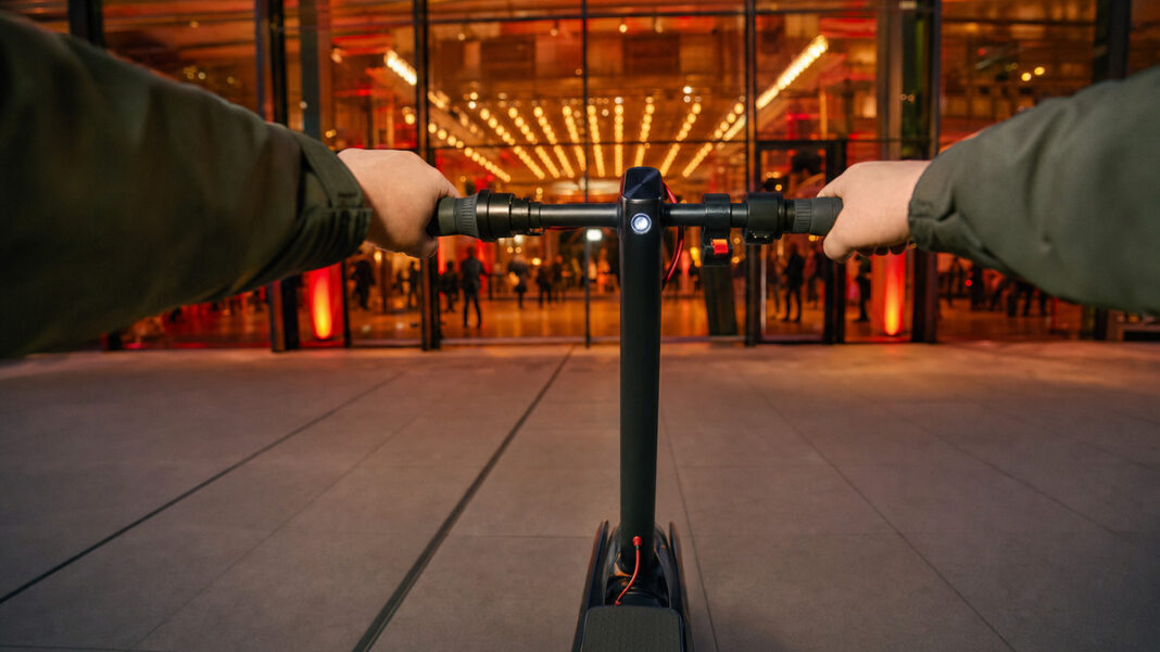 E-Scooter vor einer Berliner Eventlocation, Hände halten den Lenker