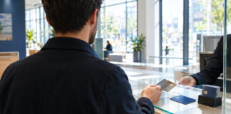 Gründer gibt in der Bank eine alte Karte ab, daneben liegt eine neue Karte im Tageslicht.