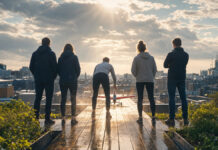 Investment für Startups trotz Corona-Krise – unmöglich? Rückenansicht eines Startup-Teams auf einer Dachterrasse neben einem kleinen Modellflieger im Sonnenlicht.