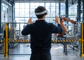 Gründer mit VR-Brille vor Testbereich in einer hellen Industriehalle