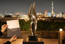 Deep Tech Awards 2020 Trophäe auf einer Rooftop-Terrasse, daneben Hände mit Einladungskarte im warmen Abendlicht