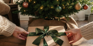 Weihnachtsgeschenk unter einem Baum, Hände schieben das Paket beiseite