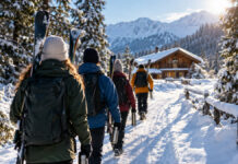 Betriebsausflug im Winter: 10 tolle Ideen für die kalte Jahreszeit Mitarbeitende gehen mit Skiern und Thermoskannen durch eine verschneite Winterlandschaft zur Hütte.