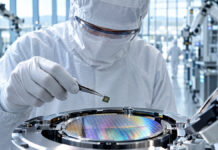 Kommt eine zweite Mikrochipkrise? Welche Rolle hat Russland für die Tech-Industrie? Techniker hält einen Mikrochip über einem Wafer in einer Halbleiter-Fertigungsanlage