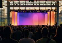 Konferenzbühne mit Publikumssilhouetten in einer hellen Messehalle