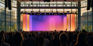 Konferenzbühne mit Publikumssilhouetten in einer hellen Messehalle