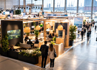 OMR Festival 2026: Bilanz und Implikationen für Gründer und Mittelstand Blick in eine Messehalle mit Gründerpaar von hinten und beleuchteten Messeständen im Tageslicht.