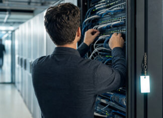 Gründer von hinten vor offenem Serverschrank im Rechenzentrum mit Netzwerkkabeln und Zugangskarte