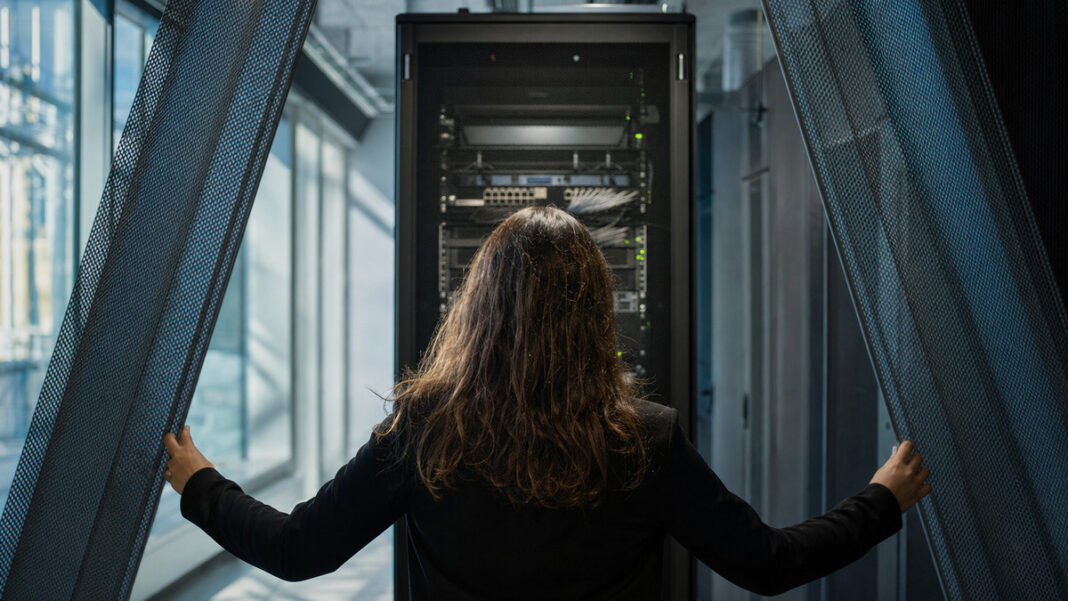 Sichere Cloud aus Hamburg Rechenraum mit Serverschrank und Person von hinten im kühlen Seitenlicht