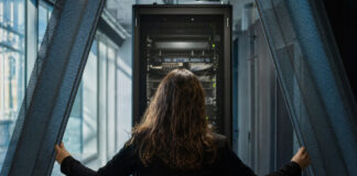 Rechenraum mit Serverschrank und Person von hinten im kühlen Seitenlicht