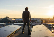 VSME-Standard 2026: Wie Startups ESG-Fragebögen ohne Reporting-Chaos beantworten Gründer prüft auf dem Dach seiner Manufaktur eine neue Solaranlage, dahinter Stadtdächer im Morgenlicht