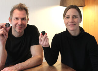 Susanne und Bernd Schmekel, die Erfinder der Sauberkugel, halten an einem Holztisch je eine Sauberkugel in die Kamera