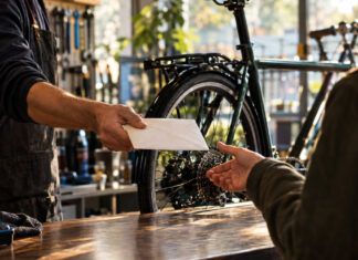 Übergabe eines Umschlags an einen Kunden in der Fahrradwerkstatt