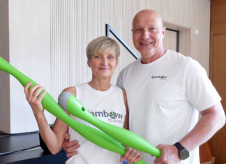 Die Ajambow-Gründer Susan Schmidt und Simon Werner halten je einen grünen, wassergefüllten Ajambow-Bogen