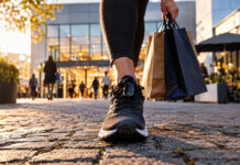 move2pay bei der Höhle der Löwen: Einkaufen mit Schritten Laufschuh mit Schrittzähler neben Einkaufstasche auf Pflaster vor Einkaufszentrum