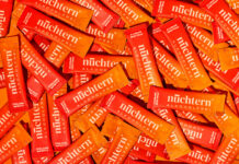 Viele Portionsbeutel des alkoholfreien Italian Spritz von nuechtern liegen dicht an dicht auf orangem Grund