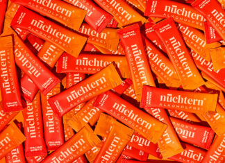 Viele Portionsbeutel des alkoholfreien Italian Spritz von nuechtern liegen dicht an dicht auf orangem Grund